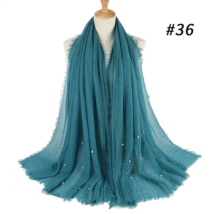 Teal lightweight scarf with pearl embellishments displayed on mannequin against white background