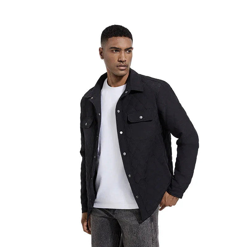 Man wearing black quilted jacket with snap buttons over white t-shirt and gray jeans