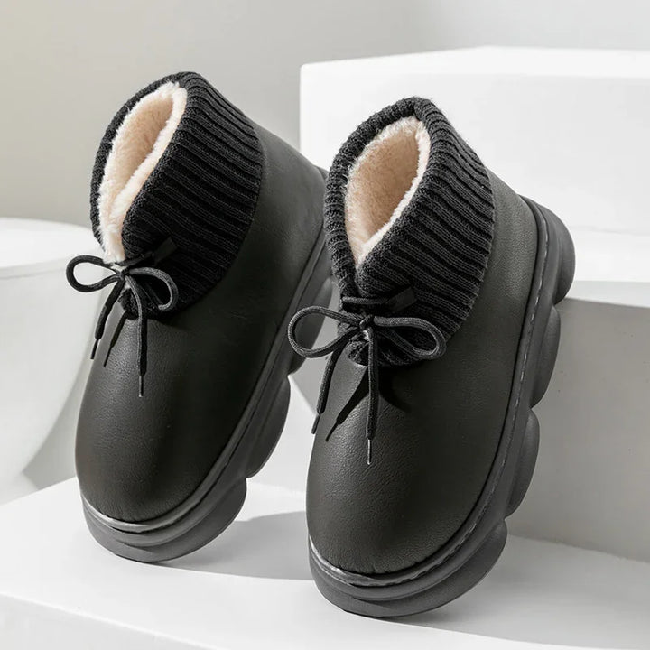 Black winter boots with thick ribbed knit cuff and soft beige fleece lining on white geometric background