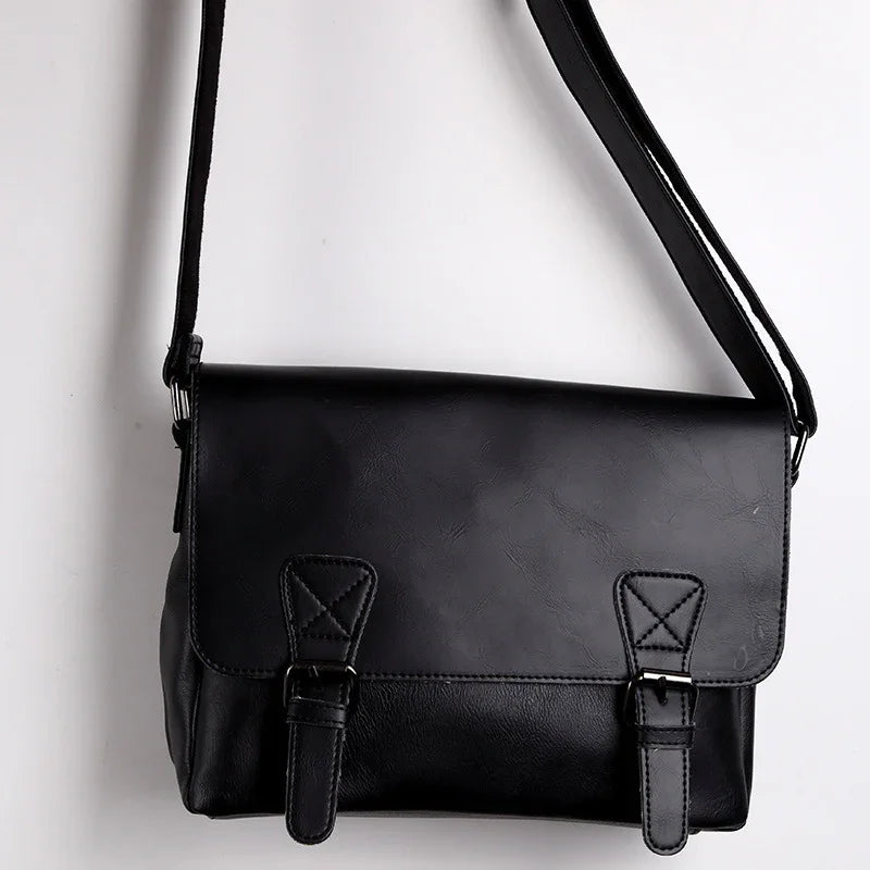 Black leather crossbody messenger bag with buckle straps on white background
