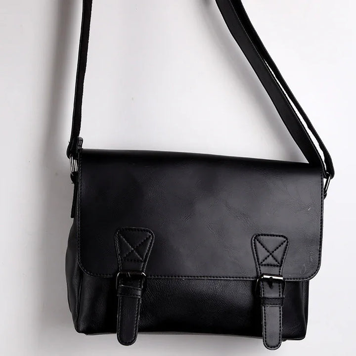 Black leather crossbody messenger bag with buckle straps on white background