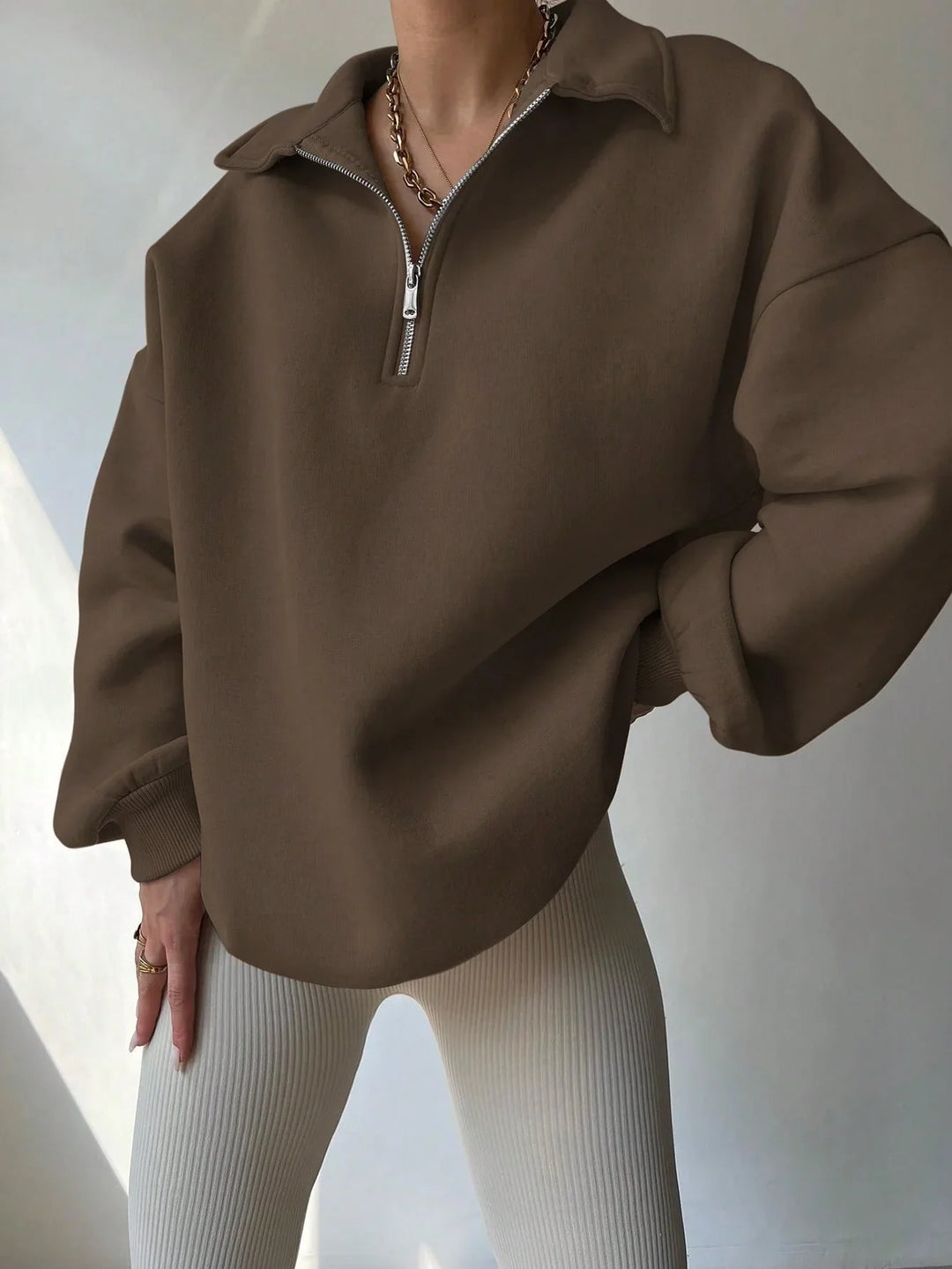 Woman wearing oversized brown half-zip pullover with ribbed beige leggings and gold necklaces