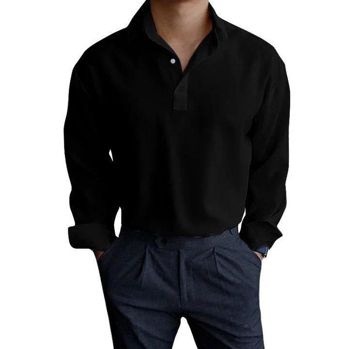 Man wearing black long-sleeve polo shirt and dark blue trousers with hands in pockets