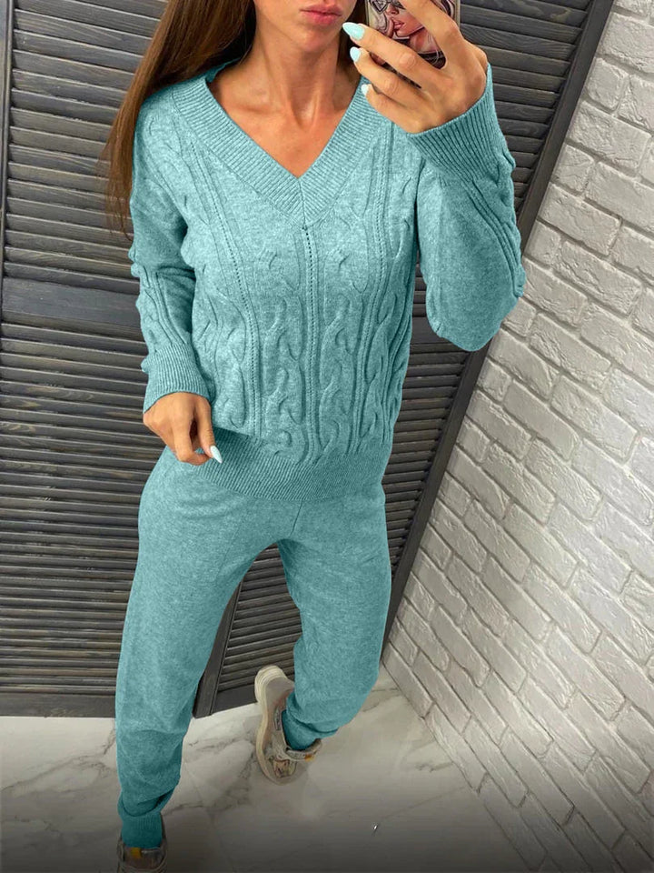 Woman wearing light blue cable knit v-neck sweater and matching knit pants in a modern room