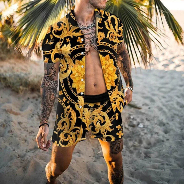 Man wearing black and gold patterned short-sleeve shirt and shorts on sandy beach with palm trees