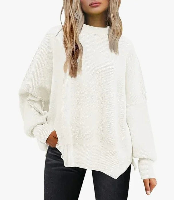 woman wearing oversized white knit sweater with long sleeves and asymmetrical hem paired with black jeans