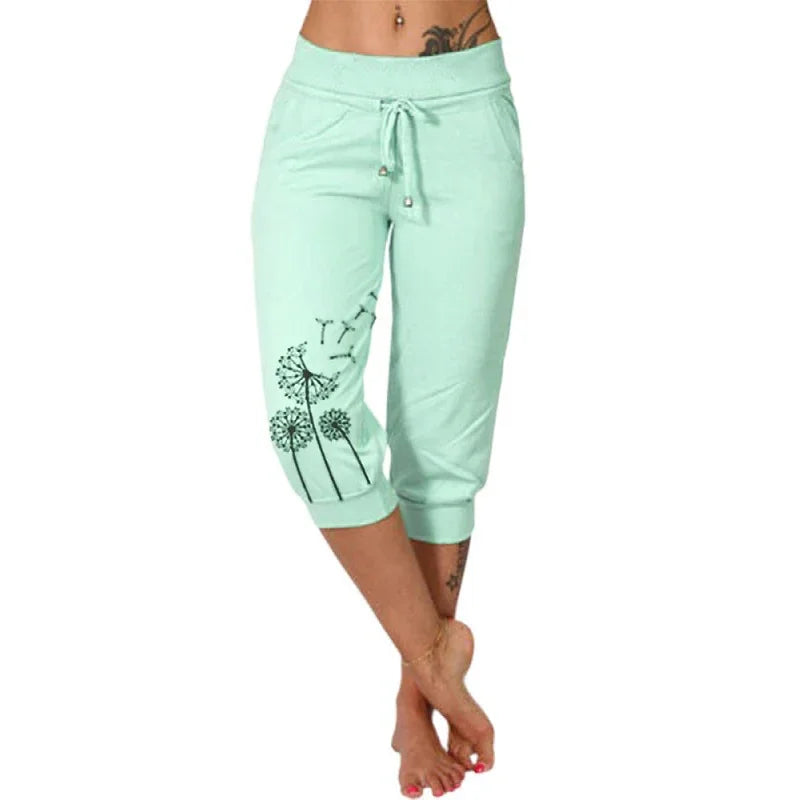 Woman wearing mint green capri sweatpants with black dandelion print and drawstring waist