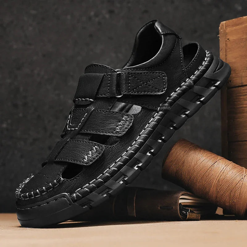 Black leather men's fisherman sandals with thick sole and stitched detailing on wooden surface