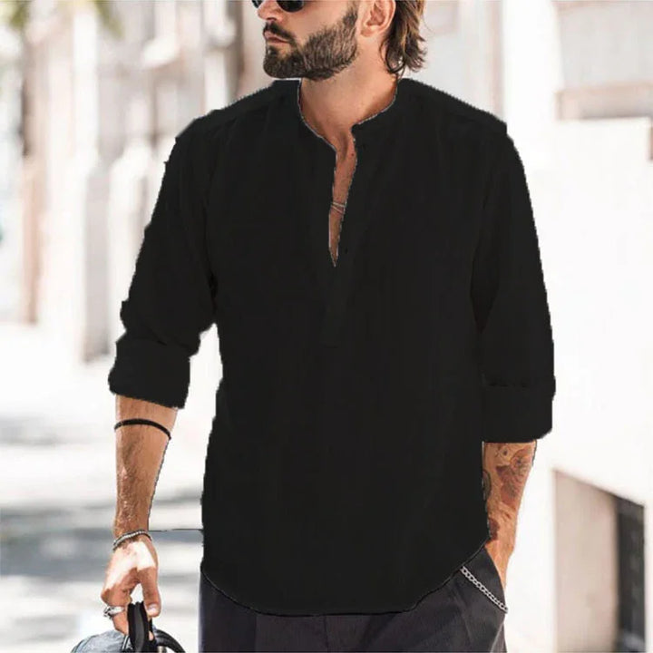 Bearded man wearing black casual shirt with rolled sleeves and sunglasses outdoors