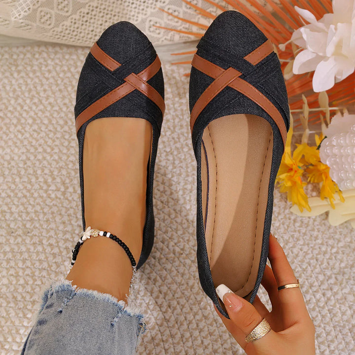 Denim flats with brown leather cross straps worn on foot with beaded anklet on textured surface