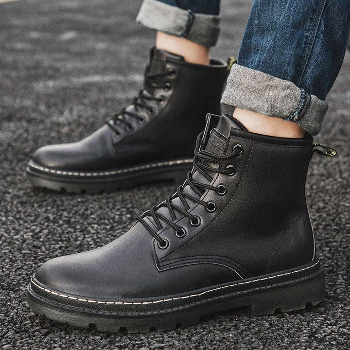 Black leather lace-up boots paired with cuffed blue jeans on asphalt surface