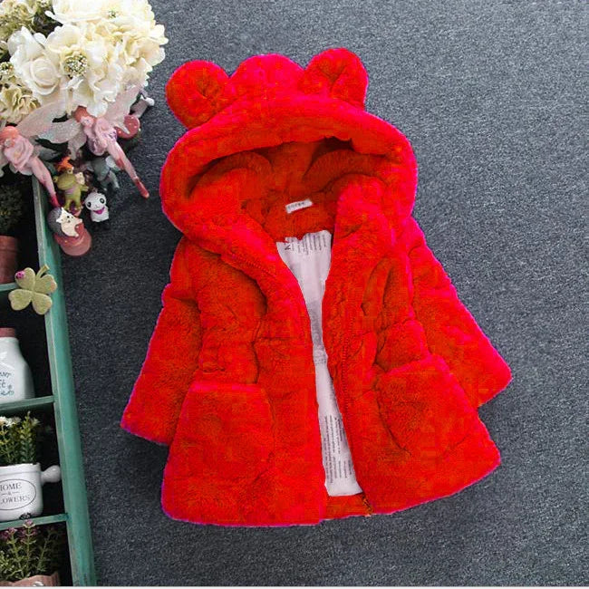 Red plush children's coat with bear ears on hood lying on gray carpet