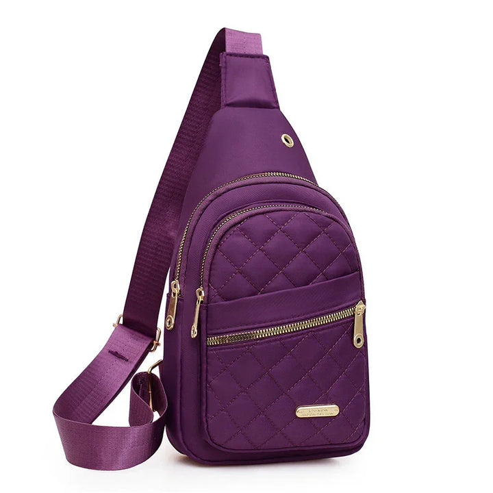 Purple quilted crossbody sling bag with gold zippers and adjustable strap