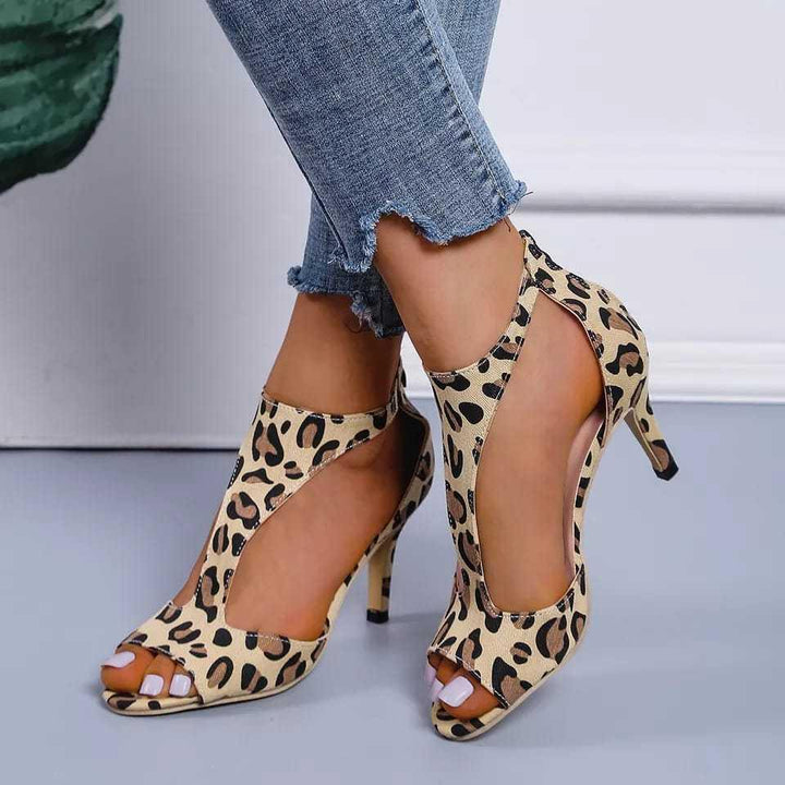 Leopard print high heel open-toe shoes worn with frayed blue jeans on a light background
