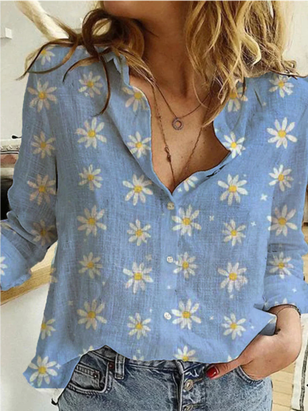 Woman wearing light blue button-up shirt with white daisy floral print and denim jeans