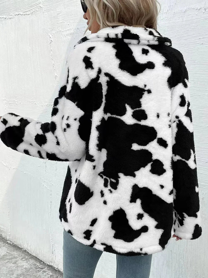 Woman wearing a cozy black and white cow print faux fur jacket standing outdoors
