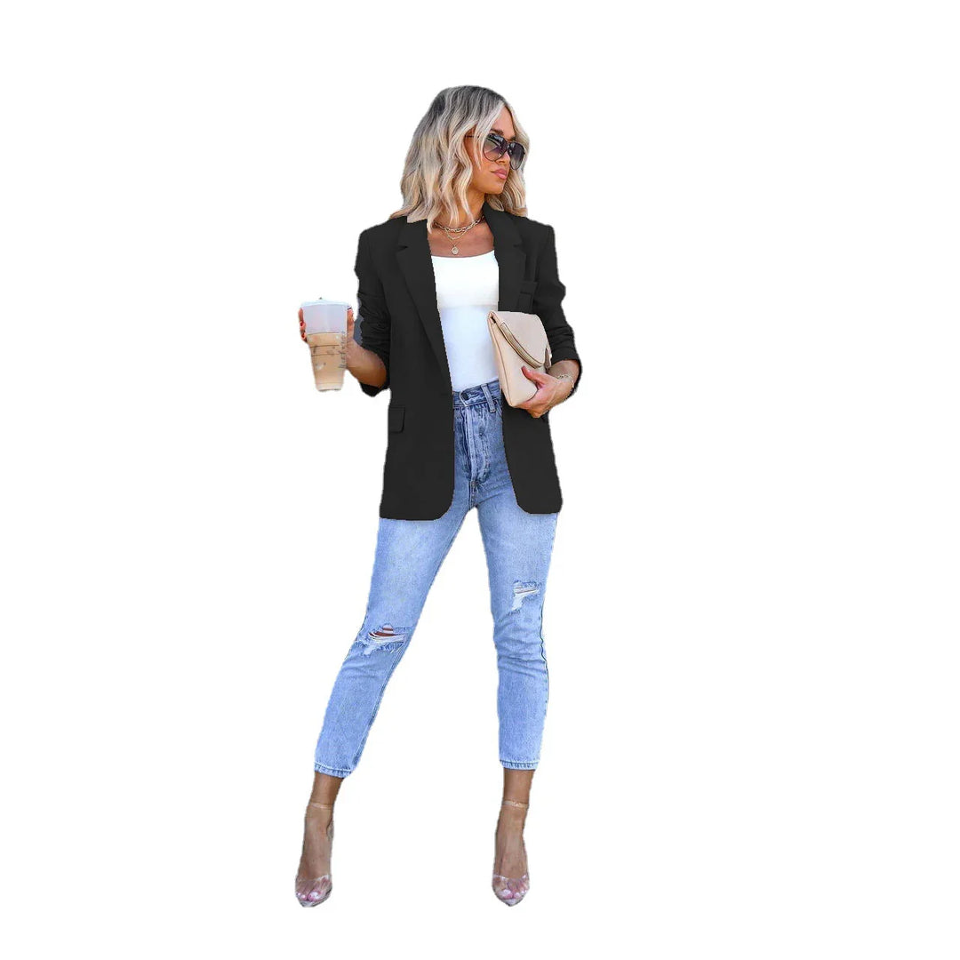 Woman in black blazer, white top, ripped jeans, clear heels holding coffee and beige clutch