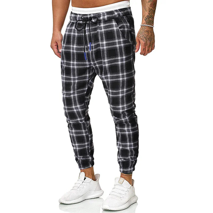 Men's black and white plaid jogger pants with drawstring waist and white sneakers