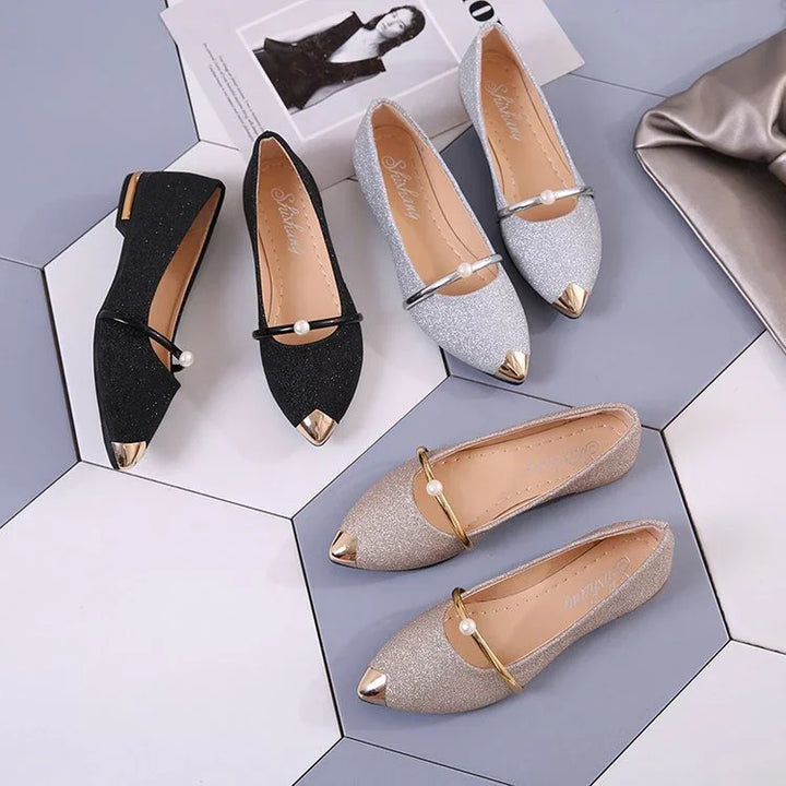 Elegant women's glitter pointed flats in black, silver, and gold with pearl-accented straps on hexagonal tiles