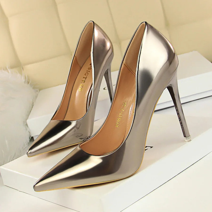 Pair of metallic silver high-heeled pointed-toe stiletto pumps on white box