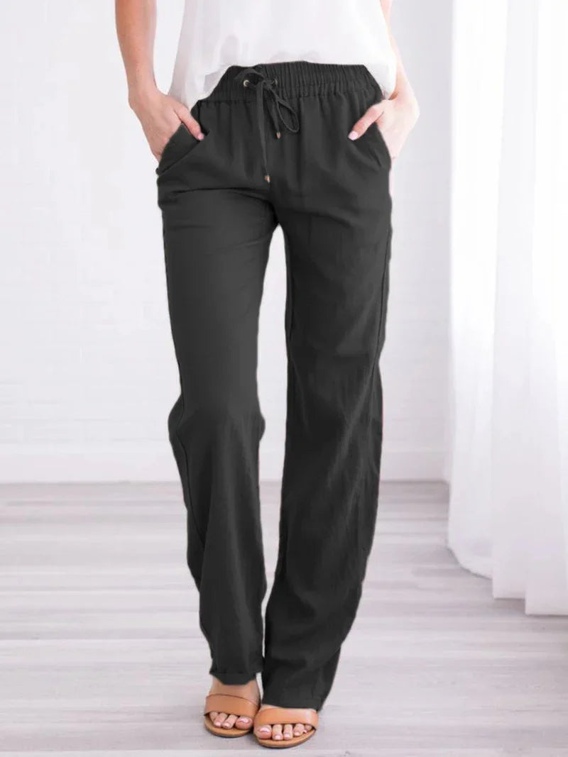 Woman wearing black drawstring lounge pants with pockets and tan sandals in bright room