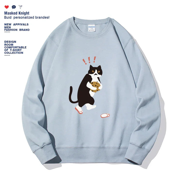 Light blue sweatshirt with cartoon black and white cat holding a cookie and surprised expression graphic