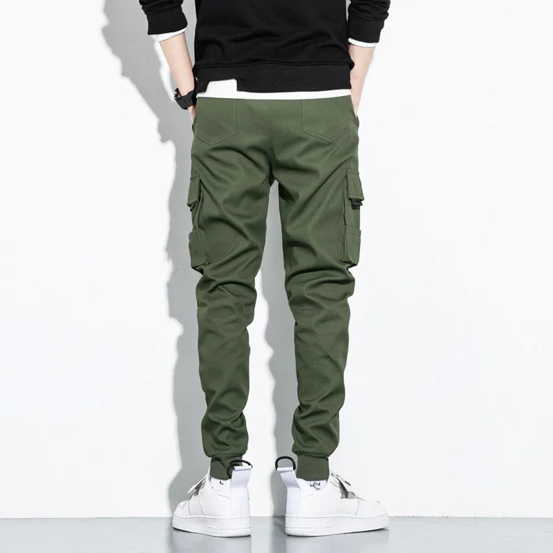 Back view of person wearing green cargo jogger pants and white sneakers against white background