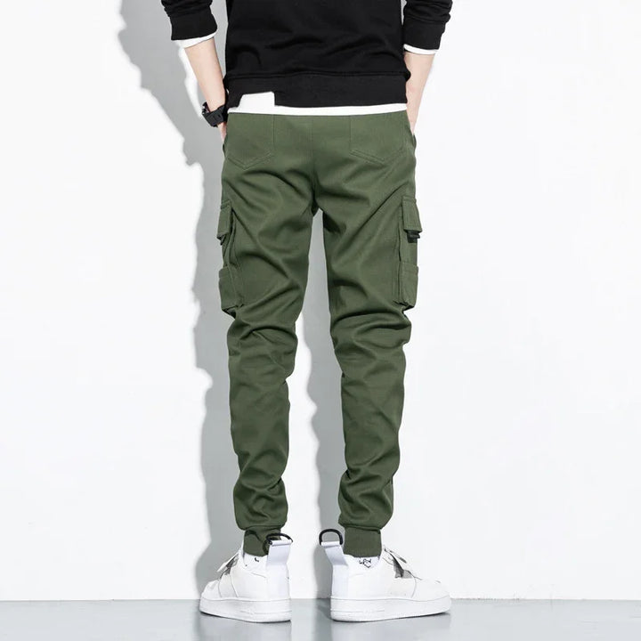 Back view of person wearing green cargo jogger pants and white sneakers against white background