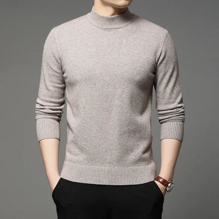 Man wearing beige turtleneck sweater with ribbed cuffs and hem, paired with black pants and a wristwatch