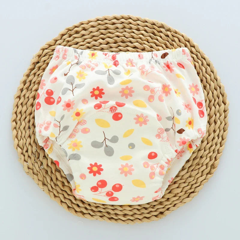 Baby bloomers with colorful floral and berry print on woven mat background