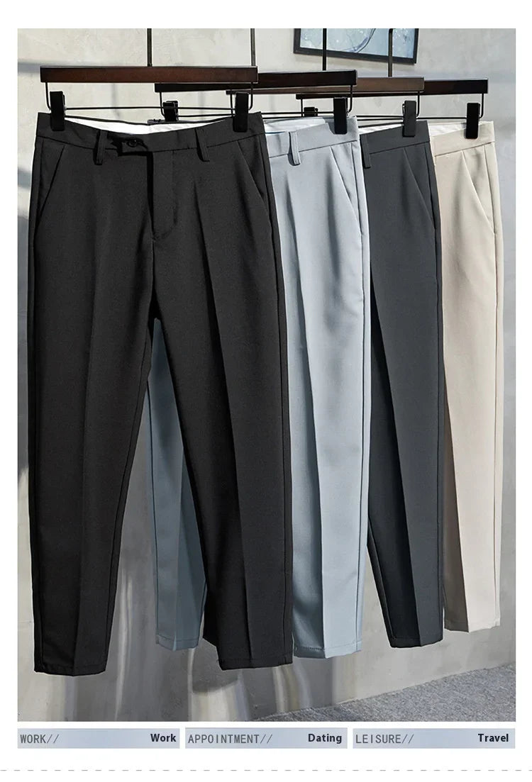Four pairs of formal men's trousers in black, light blue, gray, and beige hanging on wooden hangers