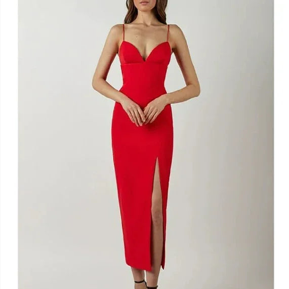 woman wearing elegant red spaghetti strap dress with front thigh slit on plain background