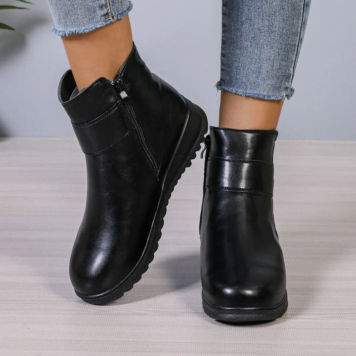 Black leather ankle boots with zipper detail worn with cropped blue jeans on light floor
