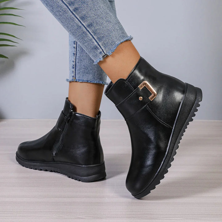 Black leather ankle boots with side zipper and gold buckle worn with cropped blue jeans