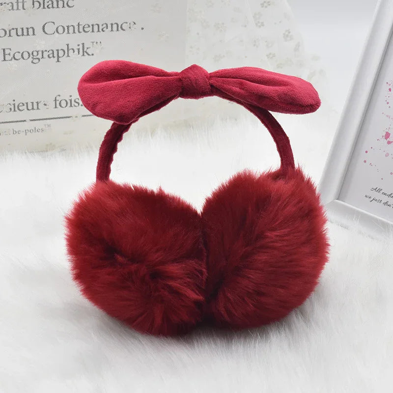 red fluffy earmuffs with a soft fabric bow headband on white fur background