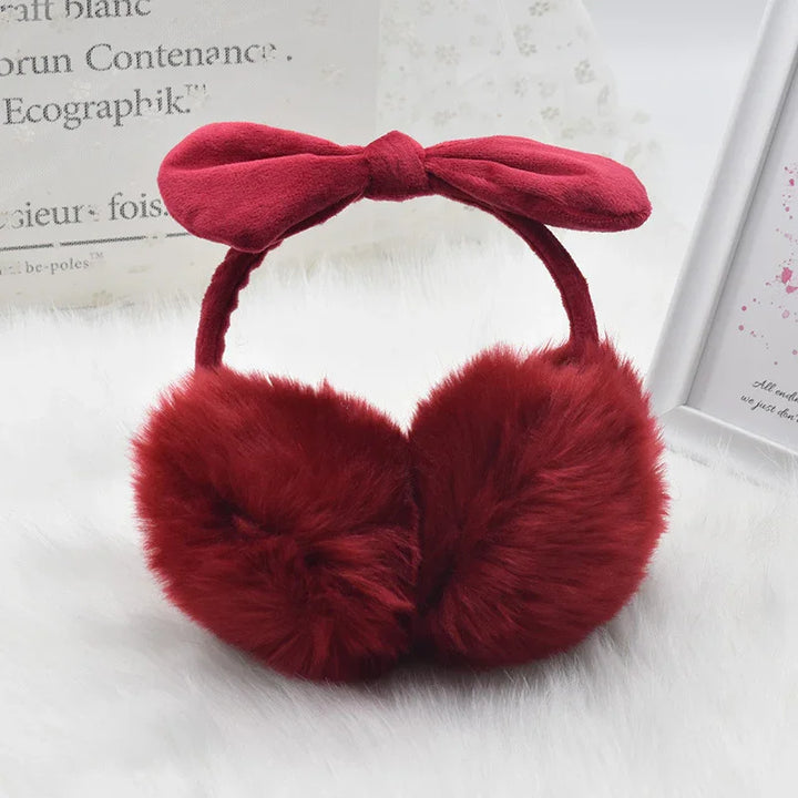 red fluffy earmuffs with a soft fabric bow headband on white fur background