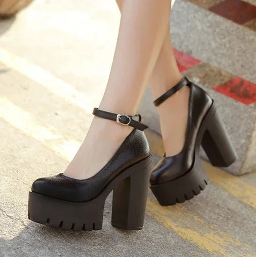 Black chunky platform heels with ankle straps on pavement with textured heels