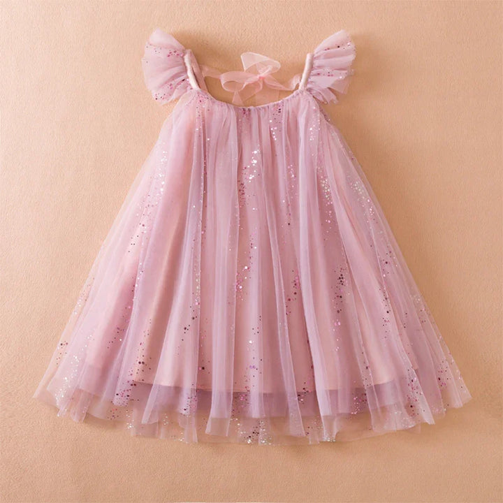 Pink glittery tulle dress with ruffled shoulders and bow tie back on beige background