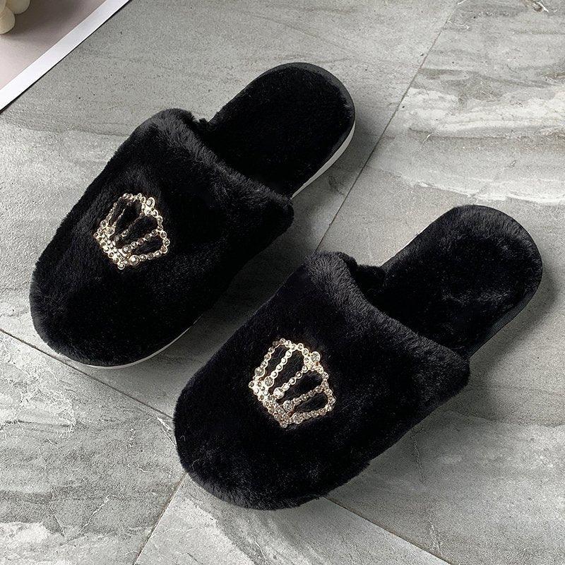 Black fuzzy slippers with golden sequin crown design on gray tile floor