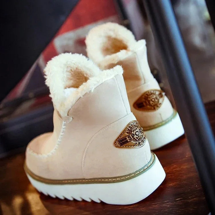 Beige winter boots with white fur lining and thick white soles on wooden floor
