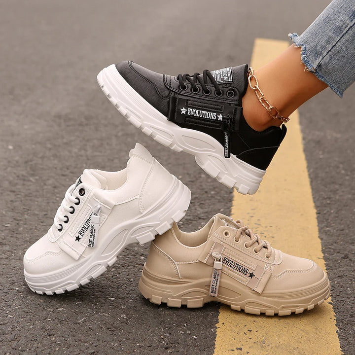 Chunky platform sneakers in black, white, and beige with zipper detail and rugged soles on asphalt