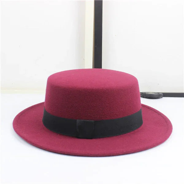 Burgundy wool fedora hat with a wide flat brim and black band detail on white background