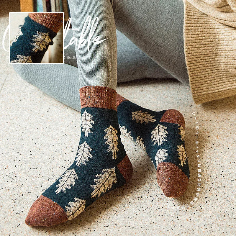 Cozy wool socks with brown accents and beige leaf patterns worn with gray leggings on speckled floor
