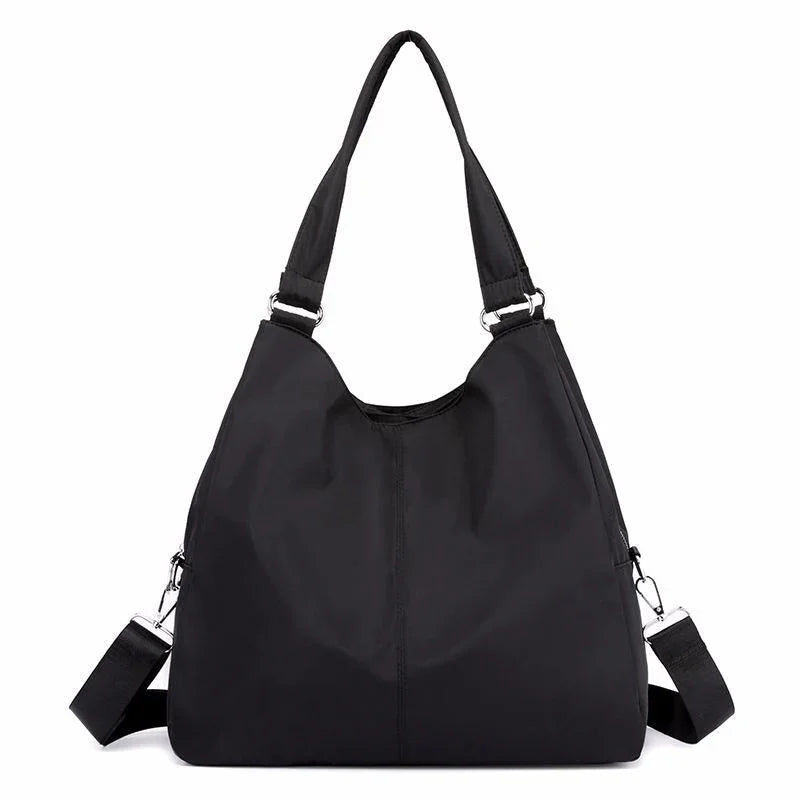 Black nylon shoulder bag with dual straps and silver hardware on a white background