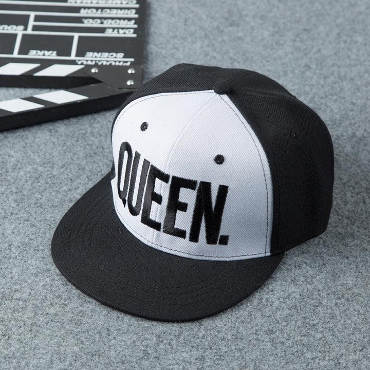 Black and white snapback cap with bold 'QUEEN.' embroidery on front panel on gray fabric