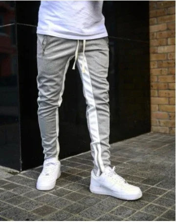 Man wearing slim fit gray jogger pants with white stripe and white sneakers outdoors