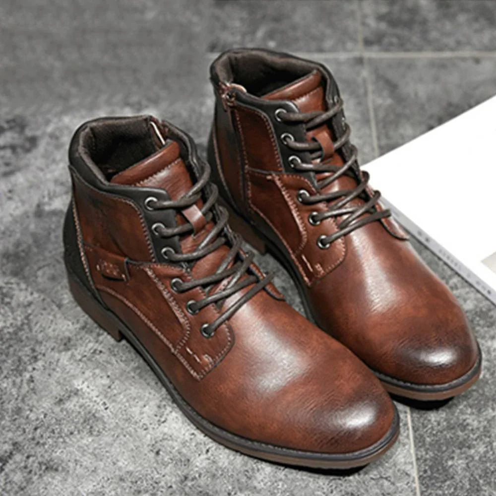 Pair of brown leather lace-up boots on gray tiled floor with book edge visible
