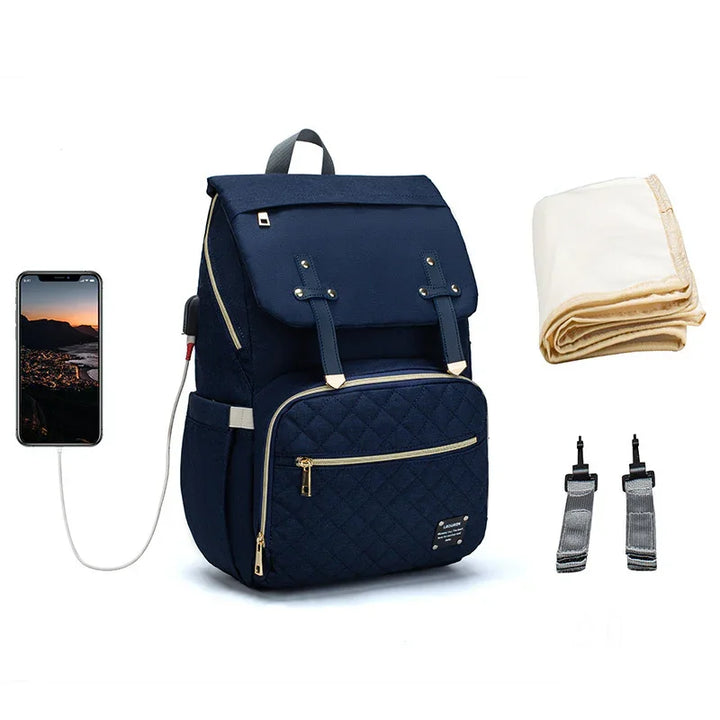 Navy blue quilted backpack with gold zippers, connected to smartphone via charging cable, with folded blanket and two stroller straps