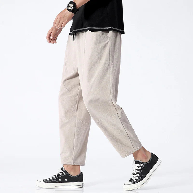 Side view of person wearing beige cropped pants, black sneakers, black watch, and black t-shirt