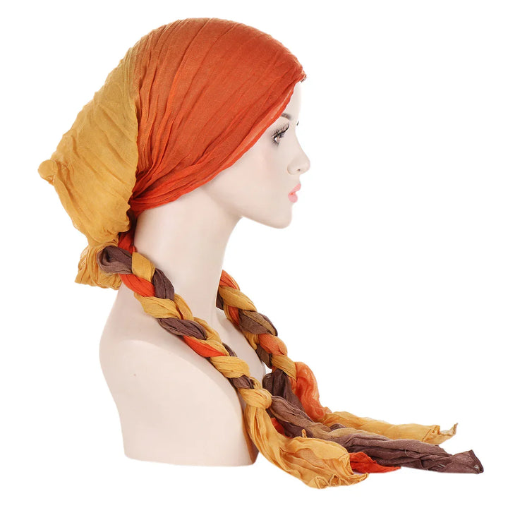 profile of mannequin head with braided orange, brown, and yellow scarf head wrap on white background